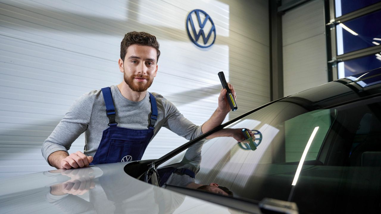 VW Service Mitarbeiter prüft ddie Frontscheibe